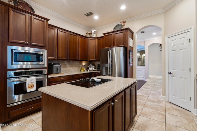 2025 Castle Point Ct, Fleming Island, FL 32003 - kitchen with stainless steel appliances, arched walkways, tasteful backsplash, light countertops, and ornamental molding