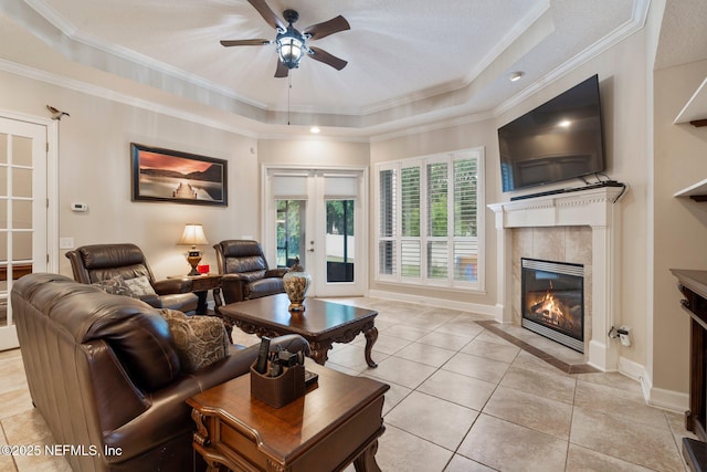 2025 Castle Point Ct, Fleming Island, FL 32003 - living area featuring a tiled fireplace, a tray ceiling, a ceiling fan, light tile patterned floors, and crown molding