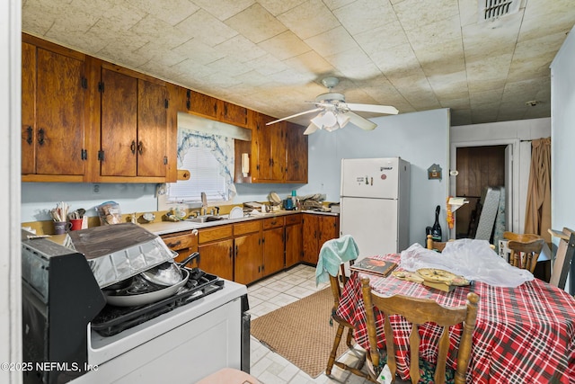 44125 Jarrett Rd, Callahan, FL 32011 - kitchen featuring freestanding refrigerator, range, ceiling fan, brown cabinets, and light countertops