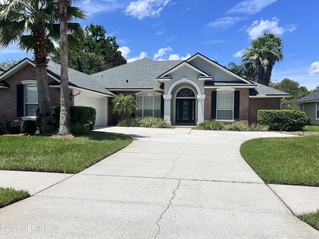 2268 S Brook Dr, Fleming Island, FL 32003 - single story home featuring concrete driveway, a garage, a front lawn, a shingled roof, and brick siding