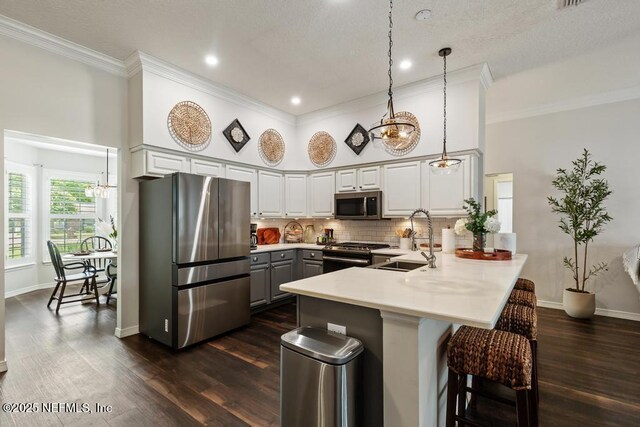 44677 Green Meadows Ln, Callahan, FL 32011 - kitchen featuring appliances with stainless steel finishes, a peninsula, a towering ceiling, a breakfast bar, and crown molding