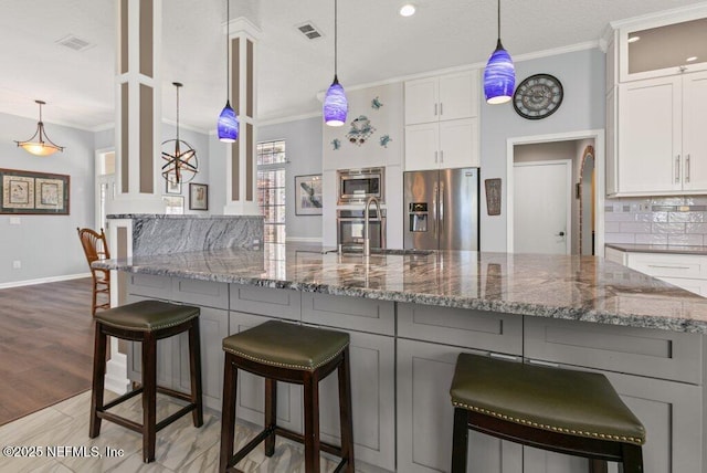 508 Lighthouse Ct, Neptune Beach, FL 32266 - kitchen with appliances with stainless steel finishes, ornamental molding, dark stone countertops, white cabinets, and tasteful backsplash
