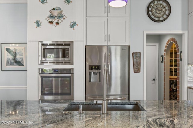 508 Lighthouse Ct, Neptune Beach, FL 32266 - kitchen with stainless steel appliances, dark stone countertops, arched walkways, and white cabinets