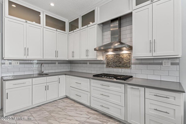 508 Lighthouse Ct, Neptune Beach, FL 32266 - kitchen with wall chimney range hood, stainless steel gas cooktop, light marble finish flooring, a textured ceiling, and glass insert cabinets