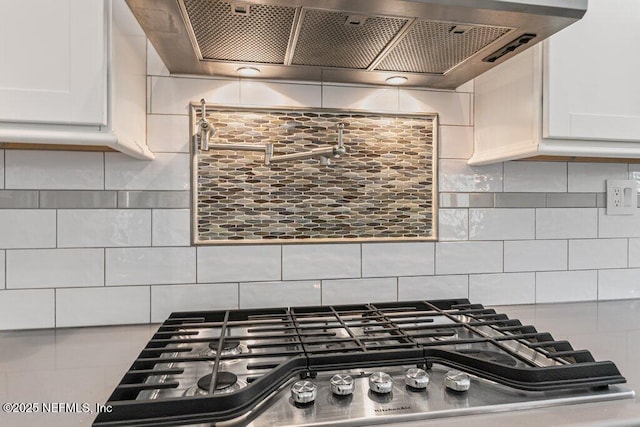 508 Lighthouse Ct, Neptune Beach, FL 32266 - kitchen view of extractor fan, stainless steel gas cooktop, white cabinetry, and backsplash