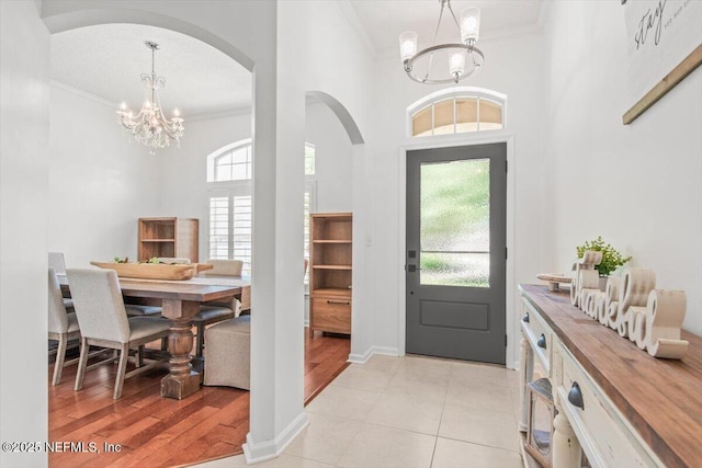 2484 Royal Pointe Dr, Green Cove Springs, FL 32043 - foyer entrance featuring a chandelier, ornamental molding, arched walkways, a towering ceiling, and light tile patterned flooring