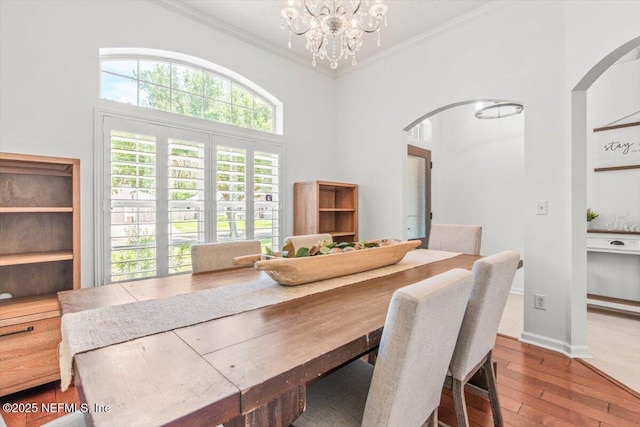 2484 Royal Pointe Dr, Green Cove Springs, FL 32043 - dining area with arched walkways, wood-type flooring, ornamental molding, a chandelier, and a towering ceiling