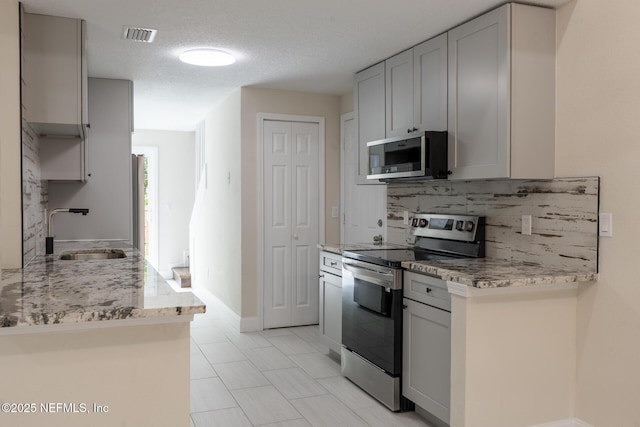 8305 Coralberry Ln, Jacksonville, FL 32244 - kitchen featuring appliances with stainless steel finishes, gray cabinets, backsplash, and light stone counters
