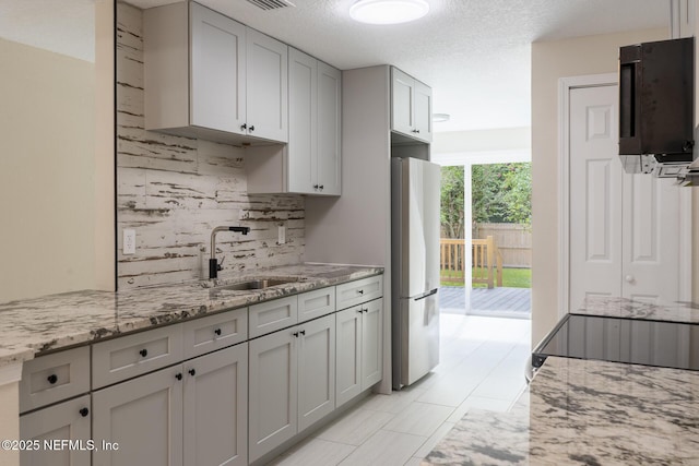 8305 Coralberry Ln, Jacksonville, FL 32244 - kitchen featuring freestanding refrigerator, decorative backsplash, light stone countertops, and gray cabinets