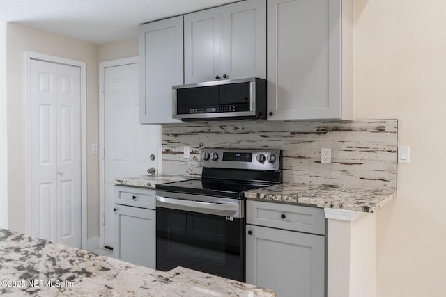 8305 Coralberry Ln, Jacksonville, FL 32244 - kitchen with stainless steel appliances, backsplash, light stone countertops, and gray cabinetry