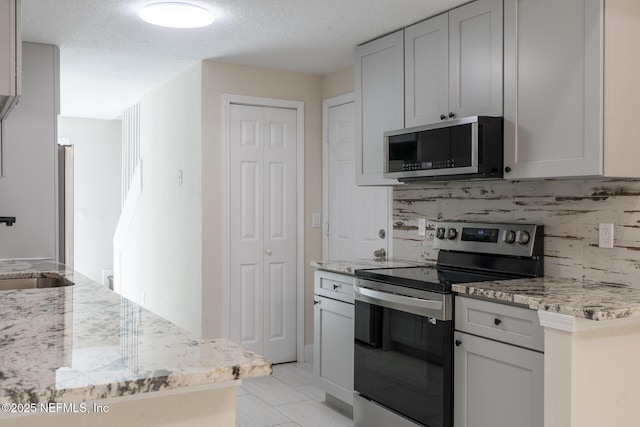8305 Coralberry Ln, Jacksonville, FL 32244 - kitchen featuring appliances with stainless steel finishes, backsplash, light stone countertops, a textured ceiling, and light tile patterned flooring