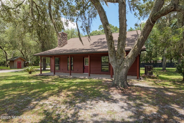 2871 Anchor Rd, Middleburg, FL 32068 - view of front facade featuring log veneer siding, a storage shed, a front lawn, a chimney, and roof with shingles