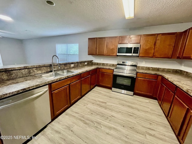 86069 Pineview Dr, Yulee, FL 32097 - kitchen featuring stainless steel appliances, light wood finished floors, a textured ceiling, dark countertops, and brown cabinets