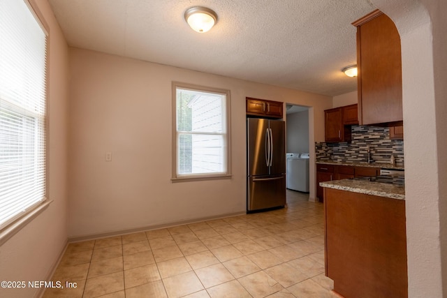 3312 Dellwood Ave, Jacksonville, FL 32205 - kitchen with freestanding refrigerator, washer / clothes dryer, tasteful backsplash, light tile patterned flooring, and brown cabinetry