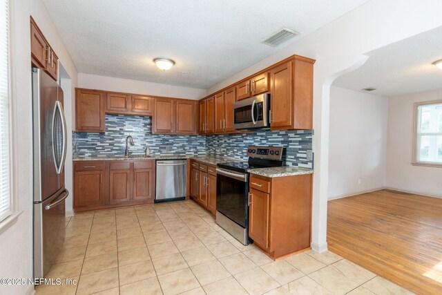 3312 Dellwood Ave, Jacksonville, FL 32205 - kitchen with appliances with stainless steel finishes, brown cabinets, light stone counters, and decorative backsplash