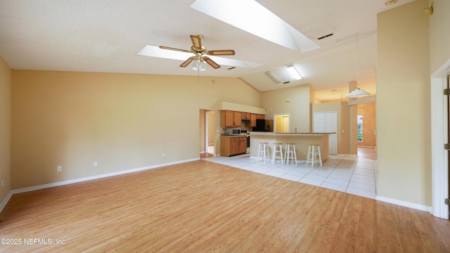 2109 Hovington Cir W, Jacksonville, FL 32246 - unfurnished living room with a skylight, light wood-style floors, vaulted ceiling, and ceiling fan