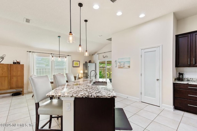 75078 Glenspring Way, Yulee, FL 32097 - kitchen featuring vaulted ceiling, a breakfast bar, light tile patterned floors, freestanding refrigerator, and light stone counters
