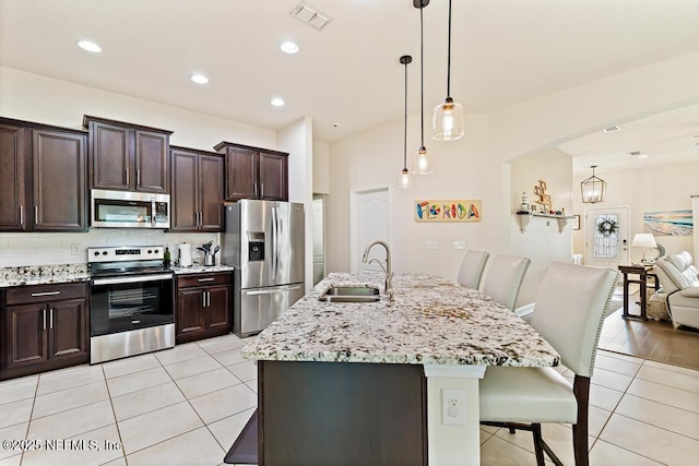 75078 Glenspring Way, Yulee, FL 32097 - kitchen with stainless steel appliances, light tile patterned floors, a kitchen breakfast bar, decorative backsplash, and light stone counters