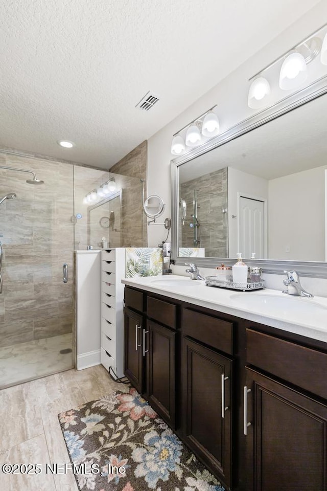 75078 Glenspring Way, Yulee, FL 32097 - bathroom with double vanity, a stall shower, and a textured ceiling