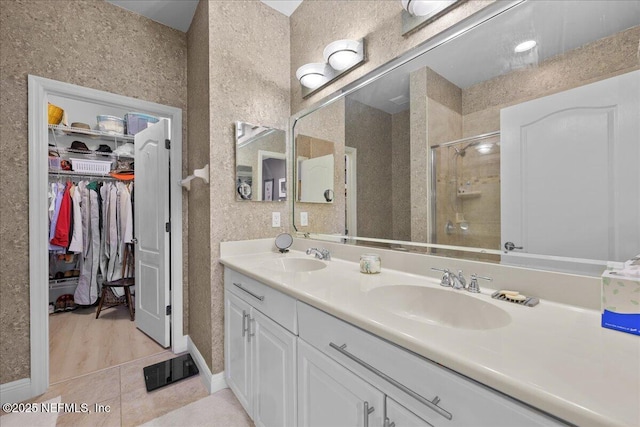 25 Riverview Bnd N Unit 122, Palm Coast, FL 32137 - bathroom with a stall shower, double vanity, a walk in closet, and tile patterned floors