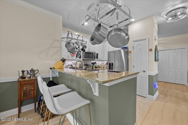 25 Riverview Bnd N Unit 122, Palm Coast, FL 32137 - kitchen featuring appliances with stainless steel finishes, a peninsula, white cabinets, light stone countertops, and backsplash