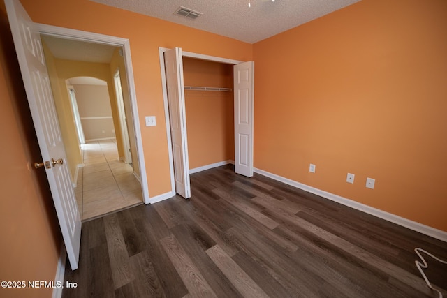 3013 Wavering Ln, Middleburg, FL 32068 - unfurnished bedroom featuring arched walkways, a textured ceiling, dark wood-style flooring, and a closet