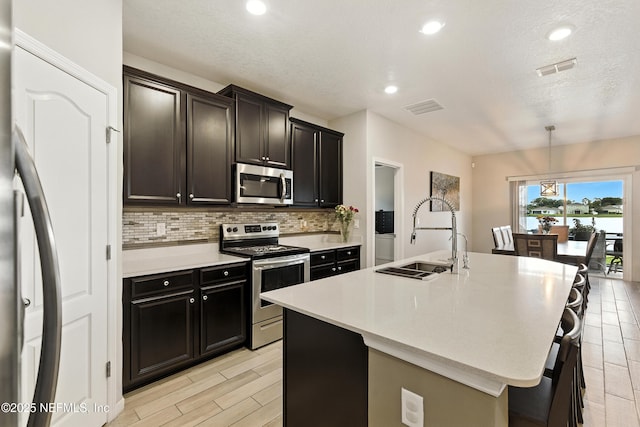 9217 Gilmore Grove Way, Jacksonville, FL 32211 - kitchen with stainless steel appliances, tasteful backsplash, light countertops, a kitchen island with sink, and recessed lighting