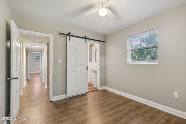 243 Ravenswood Dr, Saint Augustine, FL 32084 - unfurnished bedroom featuring wood finished floors, a barn door, and a ceiling fan