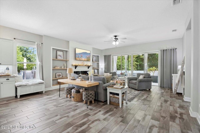 395 Jennie Lake Ct, Saint Johns, FL 32095 - living area featuring a ceiling fan, light wood finished floors, a large fireplace, plenty of natural light, and a textured ceiling