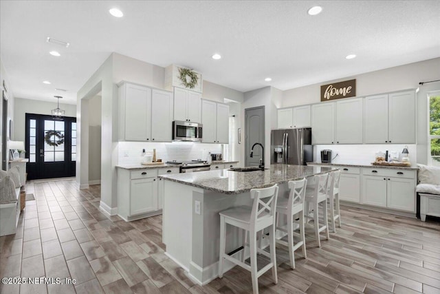 395 Jennie Lake Ct, Saint Johns, FL 32095 - kitchen featuring stainless steel appliances, backsplash, an island with sink, recessed lighting, and light stone counters