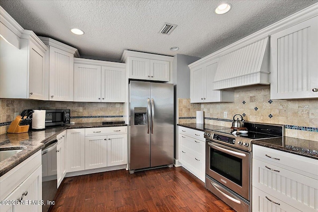 2481 S Ponte Vedra Blvd, Ponte Vedra Beach, FL 32082 - kitchen with stainless steel appliances, custom exhaust hood, dark wood-style flooring, white cabinets, and decorative backsplash