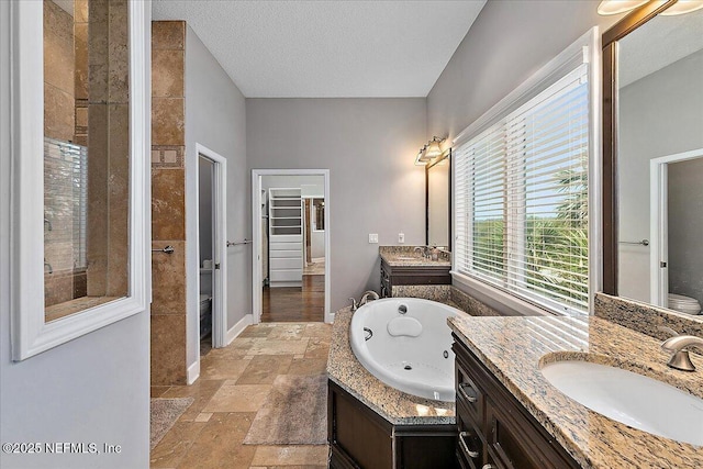 2481 S Ponte Vedra Blvd, Ponte Vedra Beach, FL 32082 - bathroom featuring a tub with jets, two vanities, stone tile floors, a textured ceiling, and a tile shower