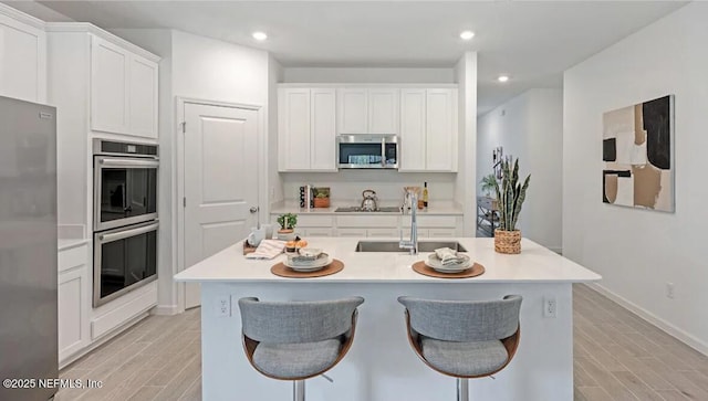 179 Charmer Trce, Saint Augustine, FL 32092 - kitchen with stainless steel appliances, light wood-style flooring, light countertops, white cabinetry, and a breakfast bar area