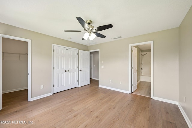 1500 Calming Water Dr Unit 4504, Fleming Island, FL 32003 - unfurnished bedroom with light wood finished floors, ensuite bathroom, multiple closets, and a ceiling fan