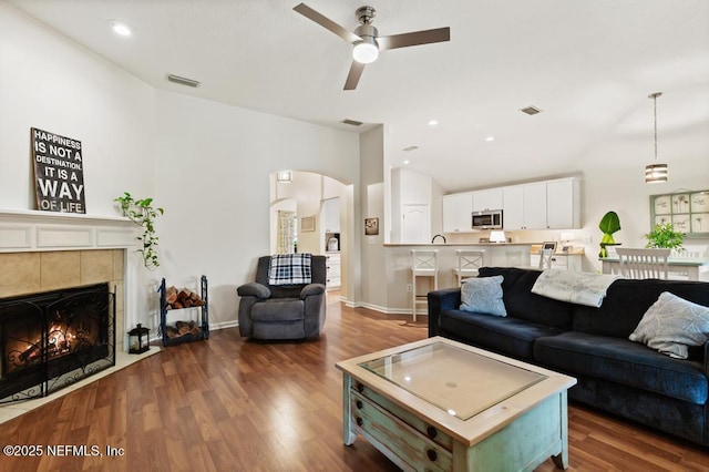 96220 Ridgewood Cir, Fernandina Beach, FL 32034 - living area with wood finished floors, arched walkways, a ceiling fan, a tiled fireplace, and recessed lighting