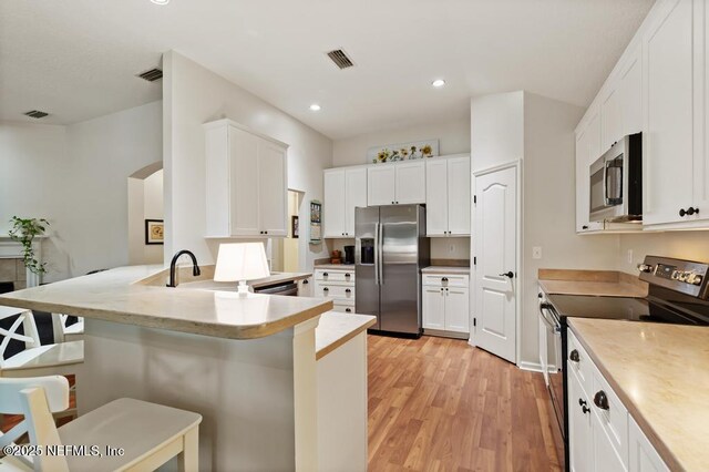 96220 Ridgewood Cir, Fernandina Beach, FL 32034 - kitchen featuring appliances with stainless steel finishes, light wood-style floors, a kitchen breakfast bar, a peninsula, and recessed lighting