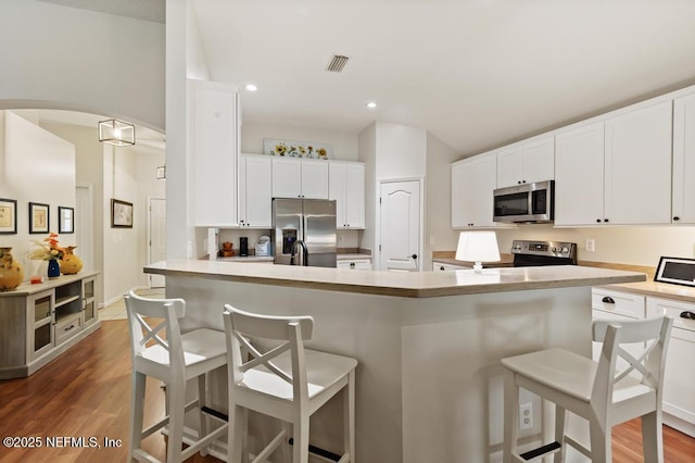 96220 Ridgewood Cir, Fernandina Beach, FL 32034 - kitchen with appliances with stainless steel finishes, a breakfast bar area, recessed lighting, white cabinets, and wood finished floors