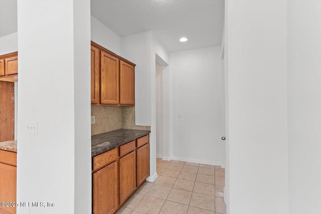 1415 Lantern Light Trl, Middleburg, FL 32068 - kitchen with tasteful backsplash, light tile patterned floors, brown cabinetry, dark stone counters, and recessed lighting
