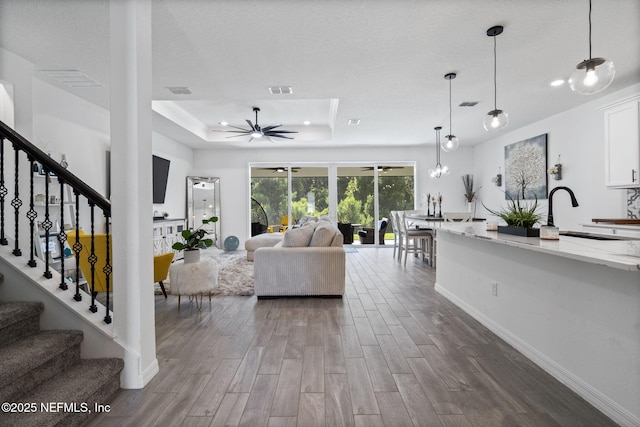 816 Blind Oak Way, Middleburg, FL 32068 - living area with a ceiling fan, a tray ceiling, dark wood finished floors, and stairway