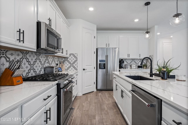 816 Blind Oak Way, Middleburg, FL 32068 - kitchen featuring stainless steel appliances, white cabinetry, pendant lighting, light wood finished floors, and light stone countertops