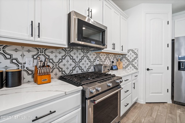 816 Blind Oak Way, Middleburg, FL 32068 - kitchen featuring stainless steel appliances, white cabinetry, tasteful backsplash, light stone countertops, and light wood finished floors