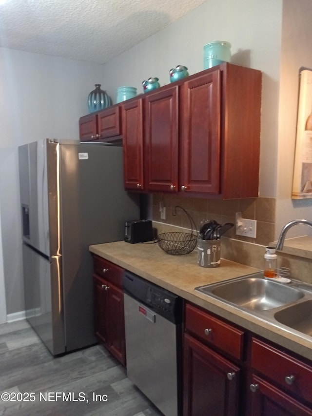 3671 Kirkpatrick Cir Unit 6, Jacksonville, FL 32210 - kitchen featuring appliances with stainless steel finishes, light wood-type flooring, a textured ceiling, dark brown cabinets, and backsplash