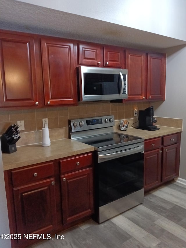 3671 Kirkpatrick Cir Unit 6, Jacksonville, FL 32210 - kitchen with stainless steel appliances, light wood finished floors, decorative backsplash, and light countertops