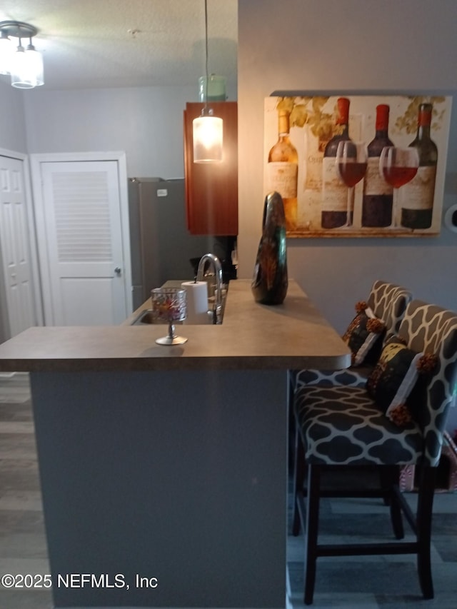 3671 Kirkpatrick Cir Unit 6, Jacksonville, FL 32210 - kitchen featuring freestanding refrigerator, a kitchen breakfast bar, wood finished floors, decorative light fixtures, and a peninsula