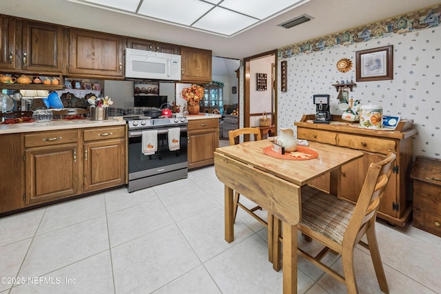 4253 Chokeberry Rd, Middleburg, FL 32068 - kitchen featuring white microwave, stainless steel range oven, light countertops, wallpapered walls, and light tile patterned flooring