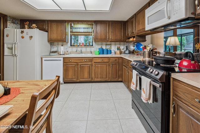4253 Chokeberry Rd, Middleburg, FL 32068 - kitchen featuring white appliances, light countertops, light tile patterned floors, and brown cabinets