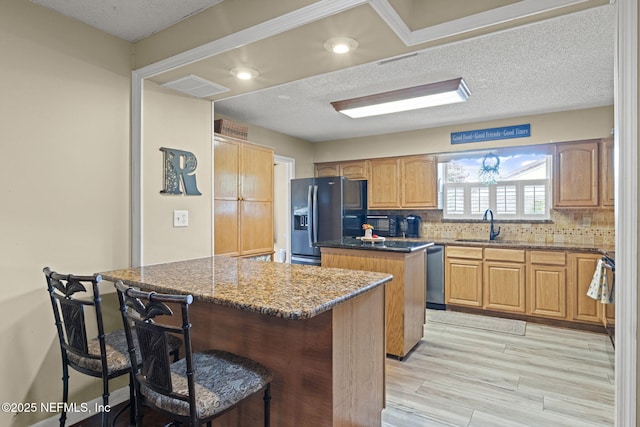 4115 Wilcrest Cir W, Jacksonville, FL 32277 - kitchen with black refrigerator with ice dispenser, a kitchen island, dishwasher, a kitchen breakfast bar, and decorative backsplash