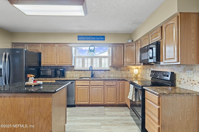 4115 Wilcrest Cir W, Jacksonville, FL 32277 - kitchen with black appliances, dark stone counters, light wood-style flooring, a textured ceiling, and backsplash