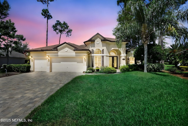 1506 Waterbridge Ct, Fleming Island, FL 32003 - mediterranean / spanish home featuring stucco siding, a garage, a lawn, and decorative driveway