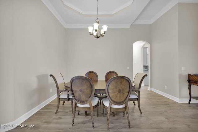 1506 Waterbridge Ct, Fleming Island, FL 32003 - dining area featuring arched walkways, a chandelier, light wood-type flooring, crown molding, and a raised ceiling